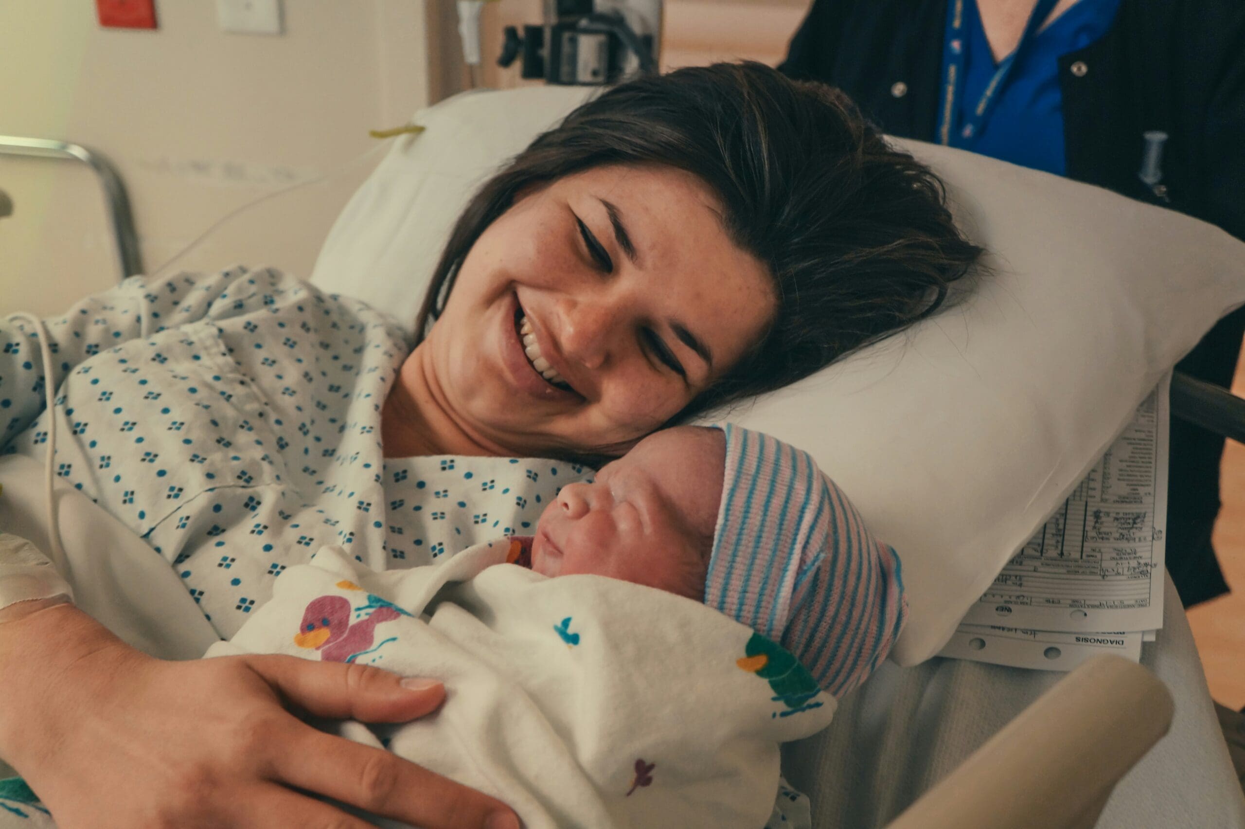 mom holding newborn baby for the first time in hospital bed